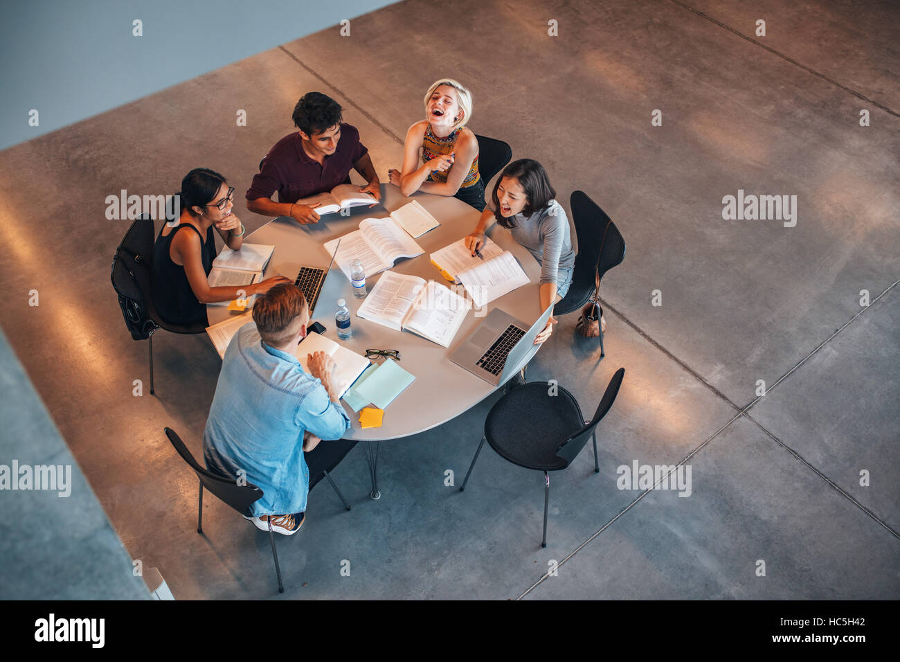 Top view of group of students sitting together at table. University students doing group study and smiling. Stock Photo