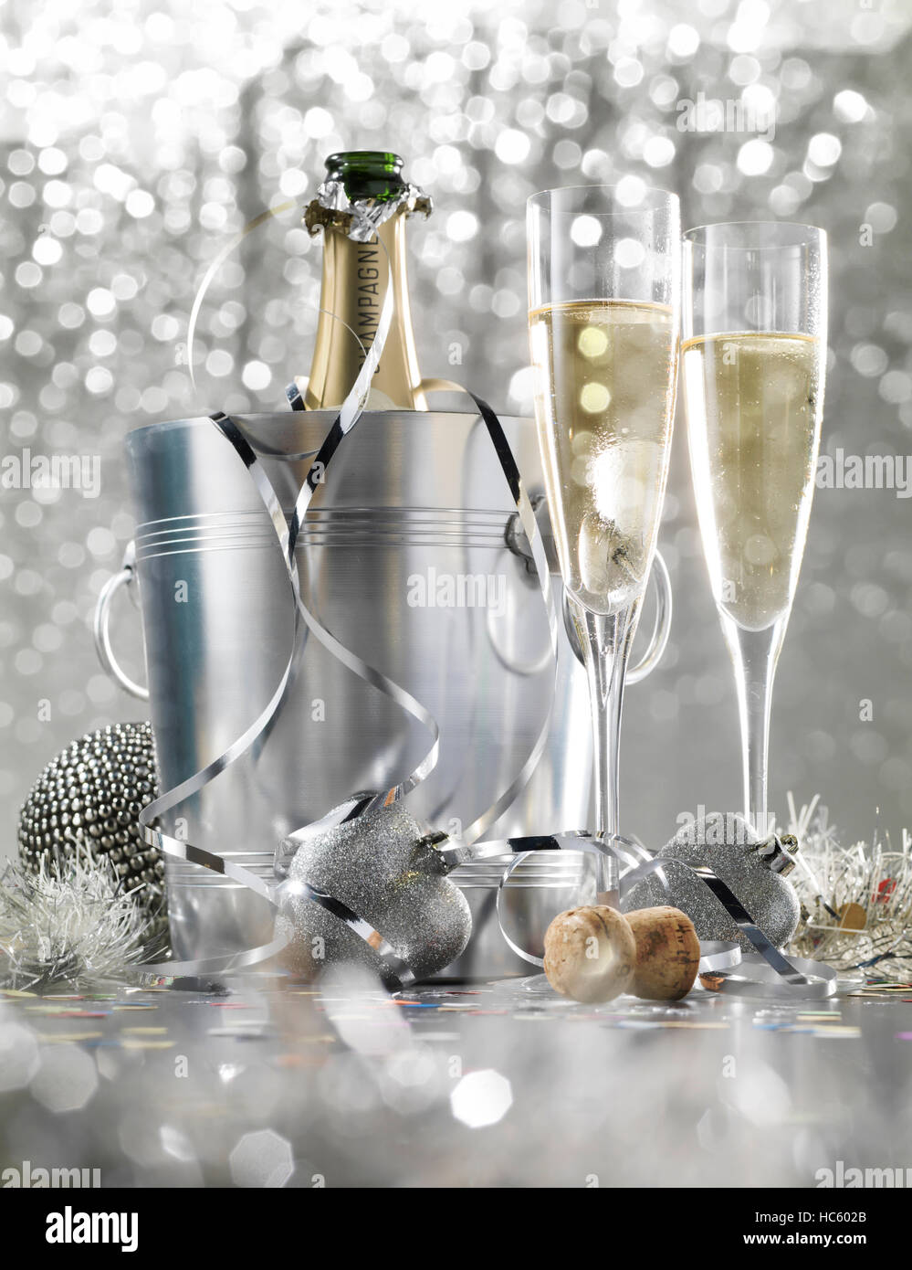 Two glasses of champagne with bottle in cooler on a silver bokeh