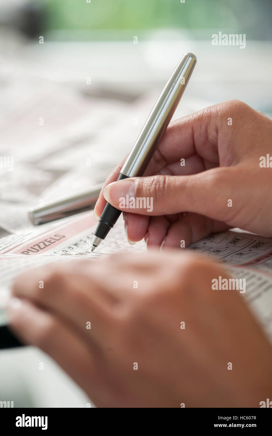 Crossword puzzle close up Hand of a young woman doing a crossword in a