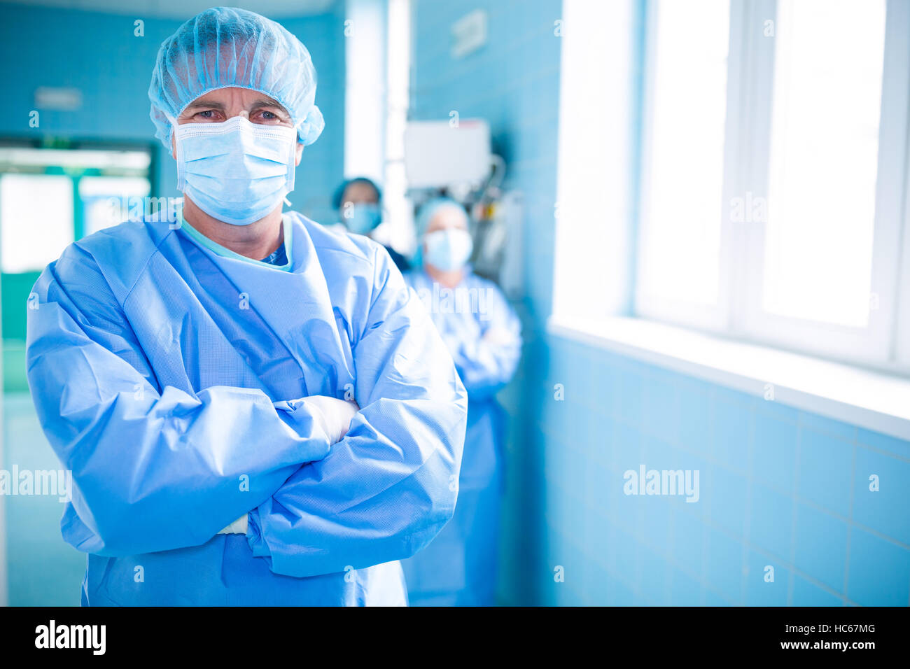 Portrait of surgeon standing with arms crossed in corridor Stock Photo ...
