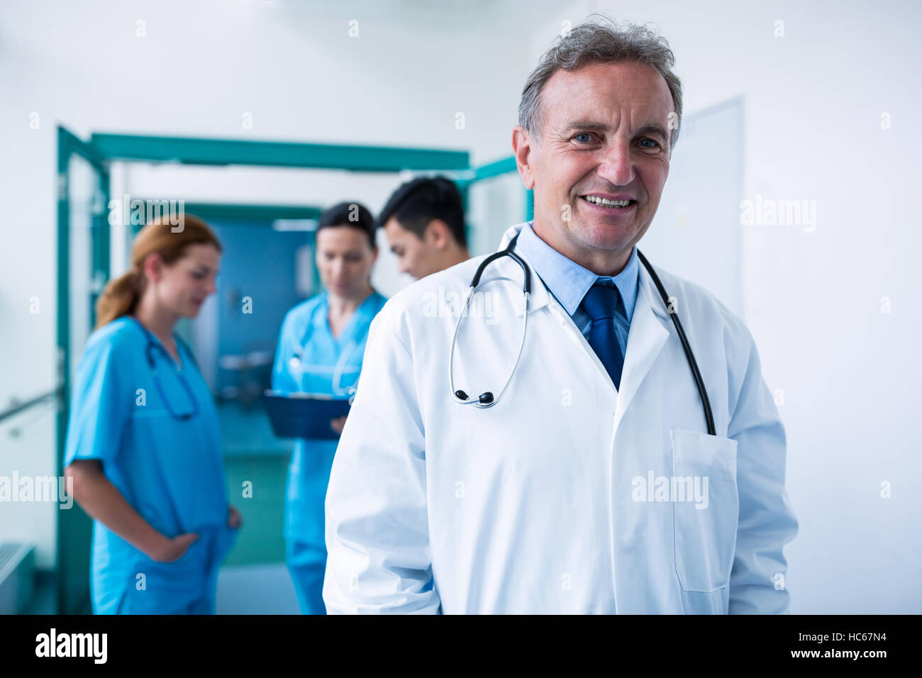 Portrait of smiling doctor standing in corridor Stock Photo - Alamy