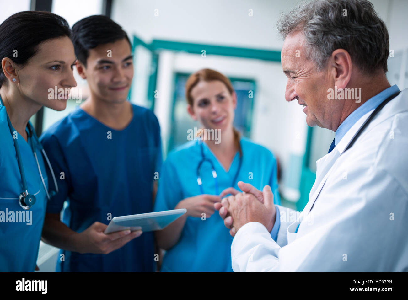 Doctor and surgeons interacting wit each other in corridor Stock Photo ...
