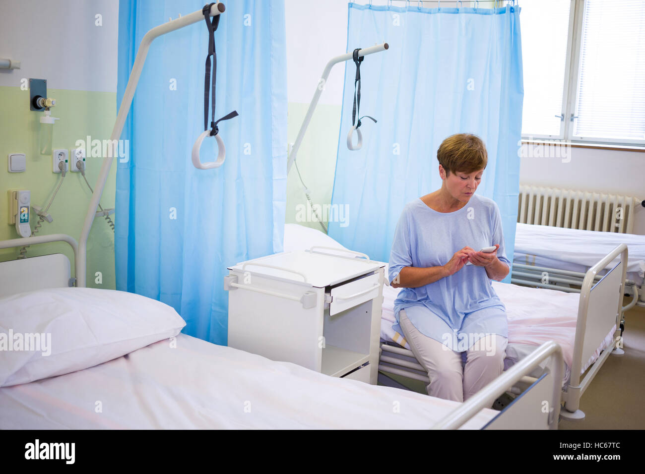 Sad senior patient using mobile phone Stock Photo