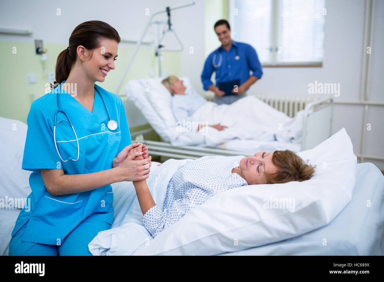 Nurse consoling a patient in hospital ward Stock Photo