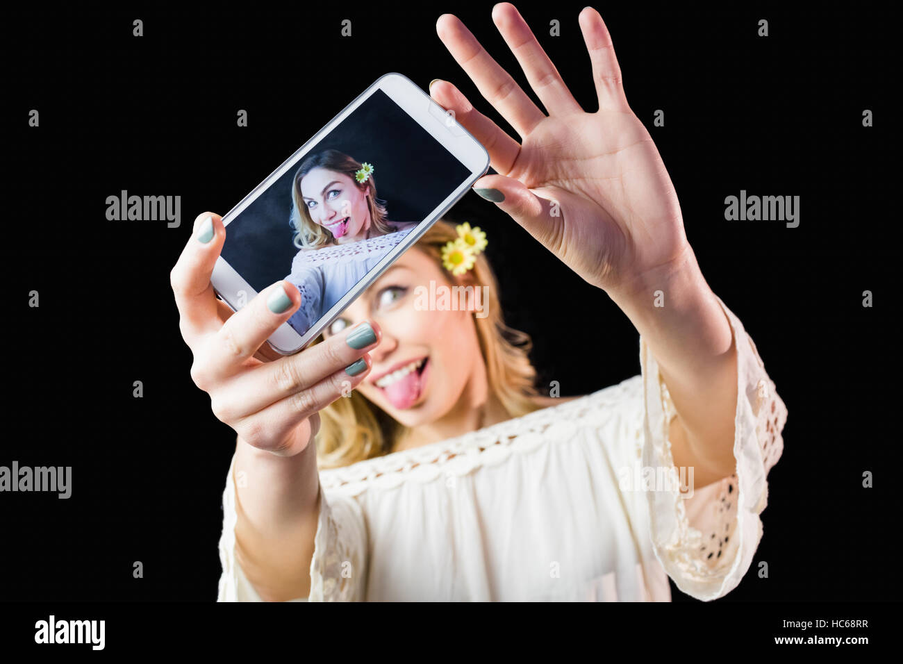 Smiling woman clicking photo from mobile phone against black background Stock Photo
