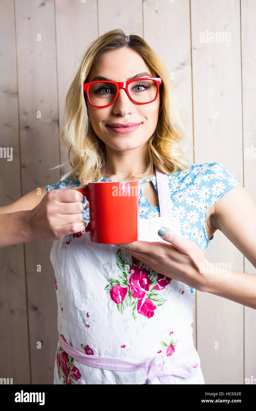 Smiling woman in apron holding a coffee mug against texture background Stock Photo