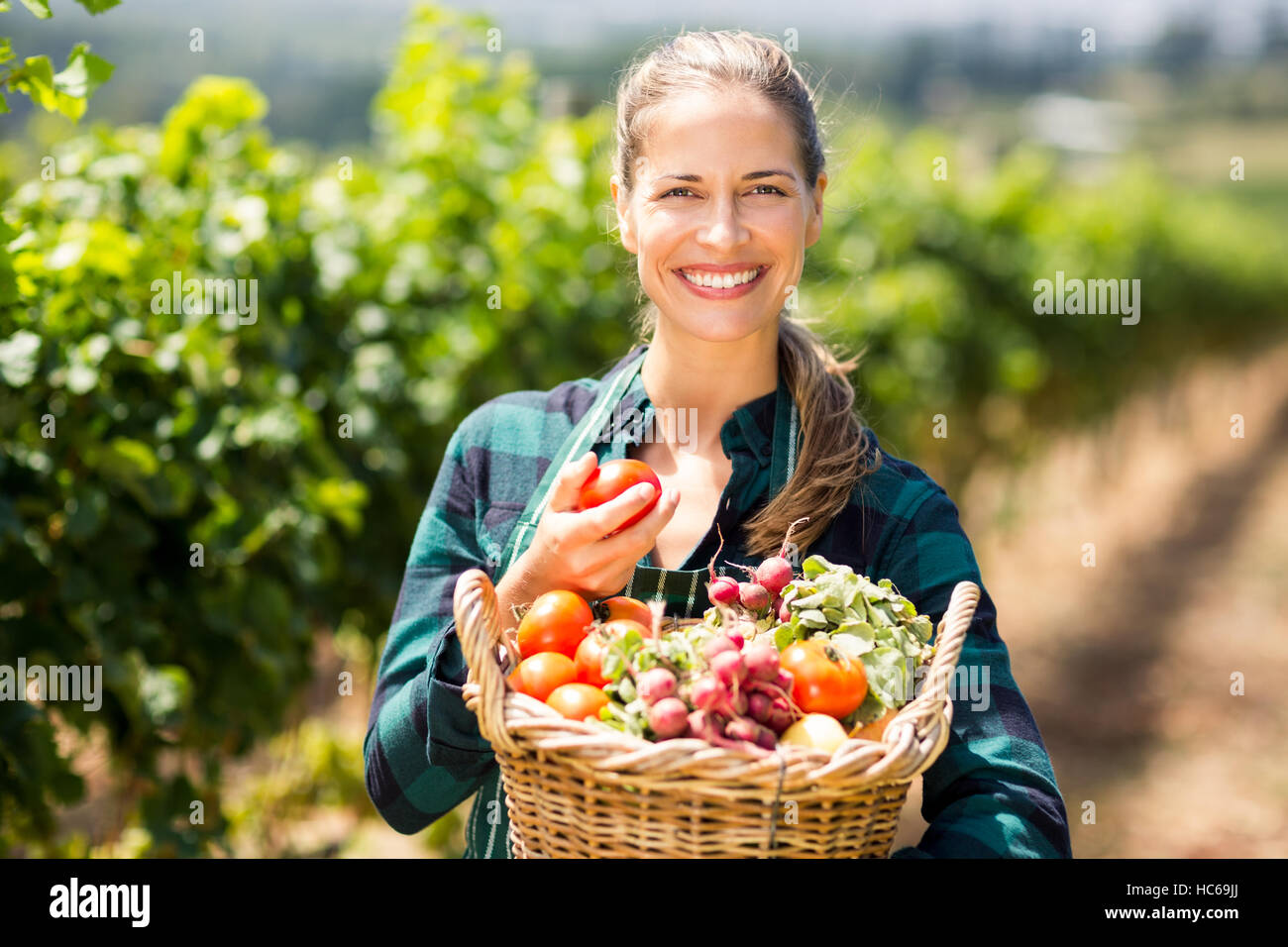 Portrait of happy female farmer holding a basket of vegetables Stock ...