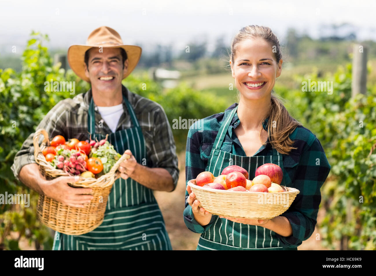 Portrait of happy farmer couple holding baskets of vegetables and fruits Stock Photo