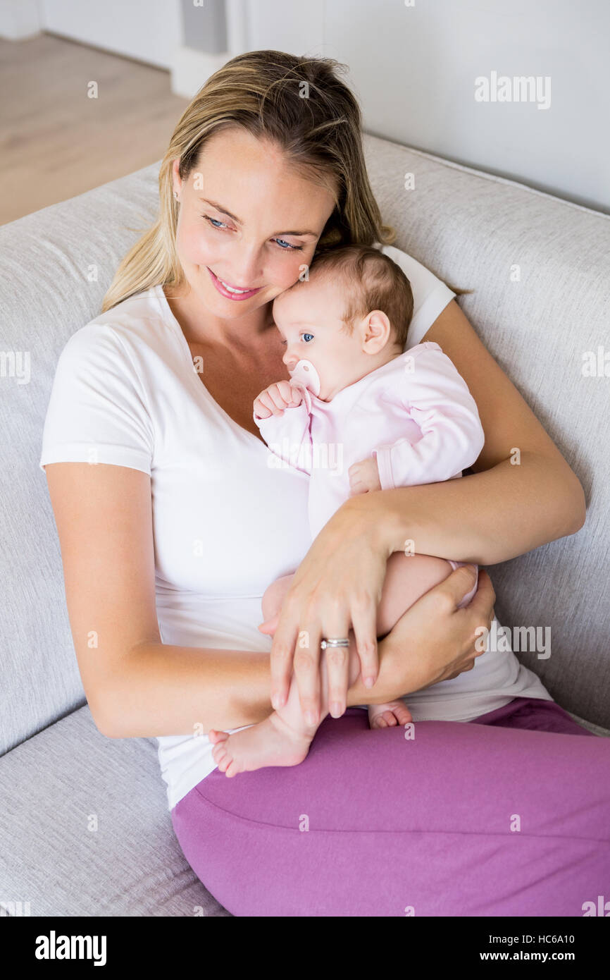 Mother sitting with her baby on sofa in living room Stock Photo