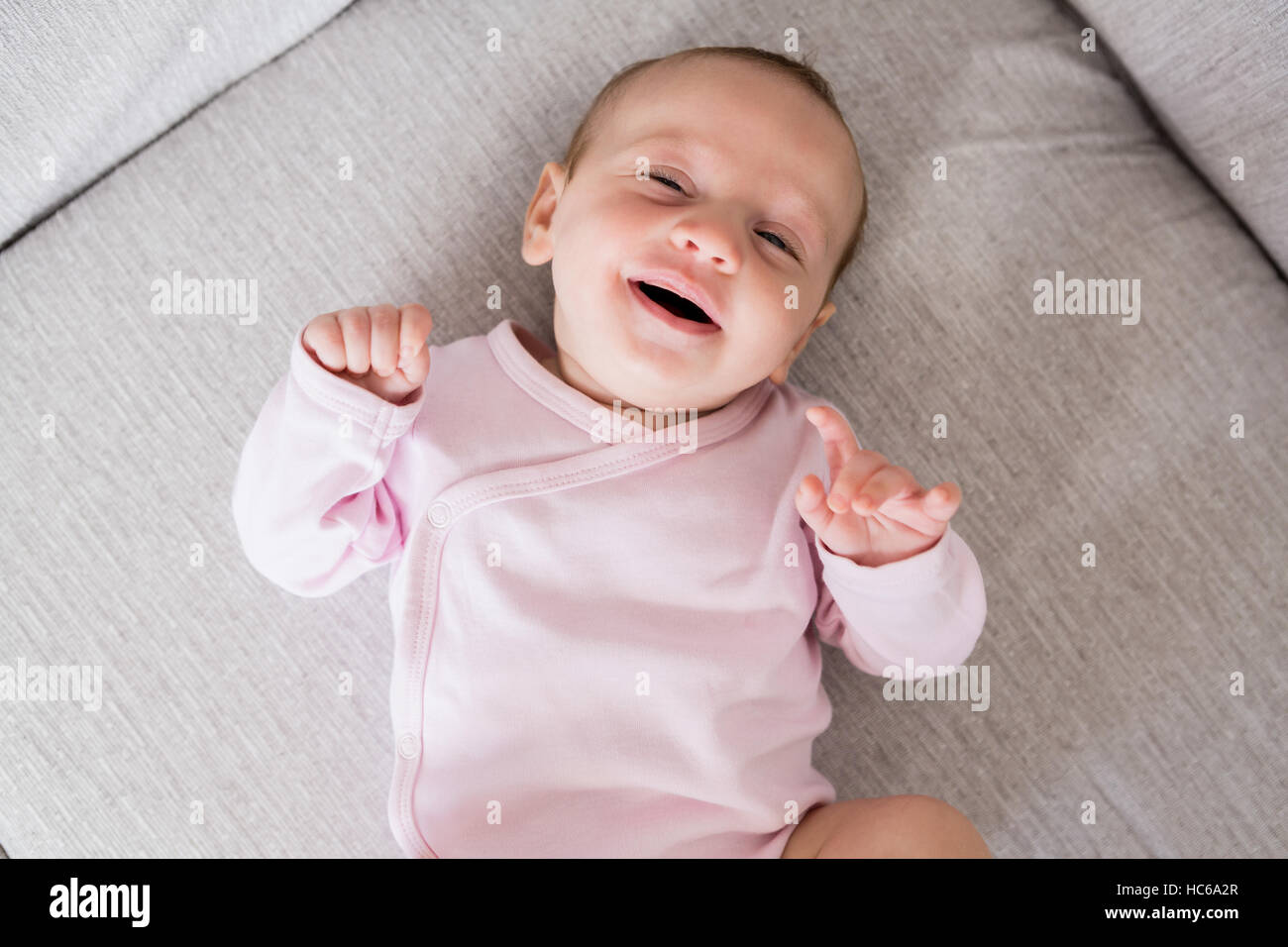 Smiling baby lying on sofa in living room Stock Photo