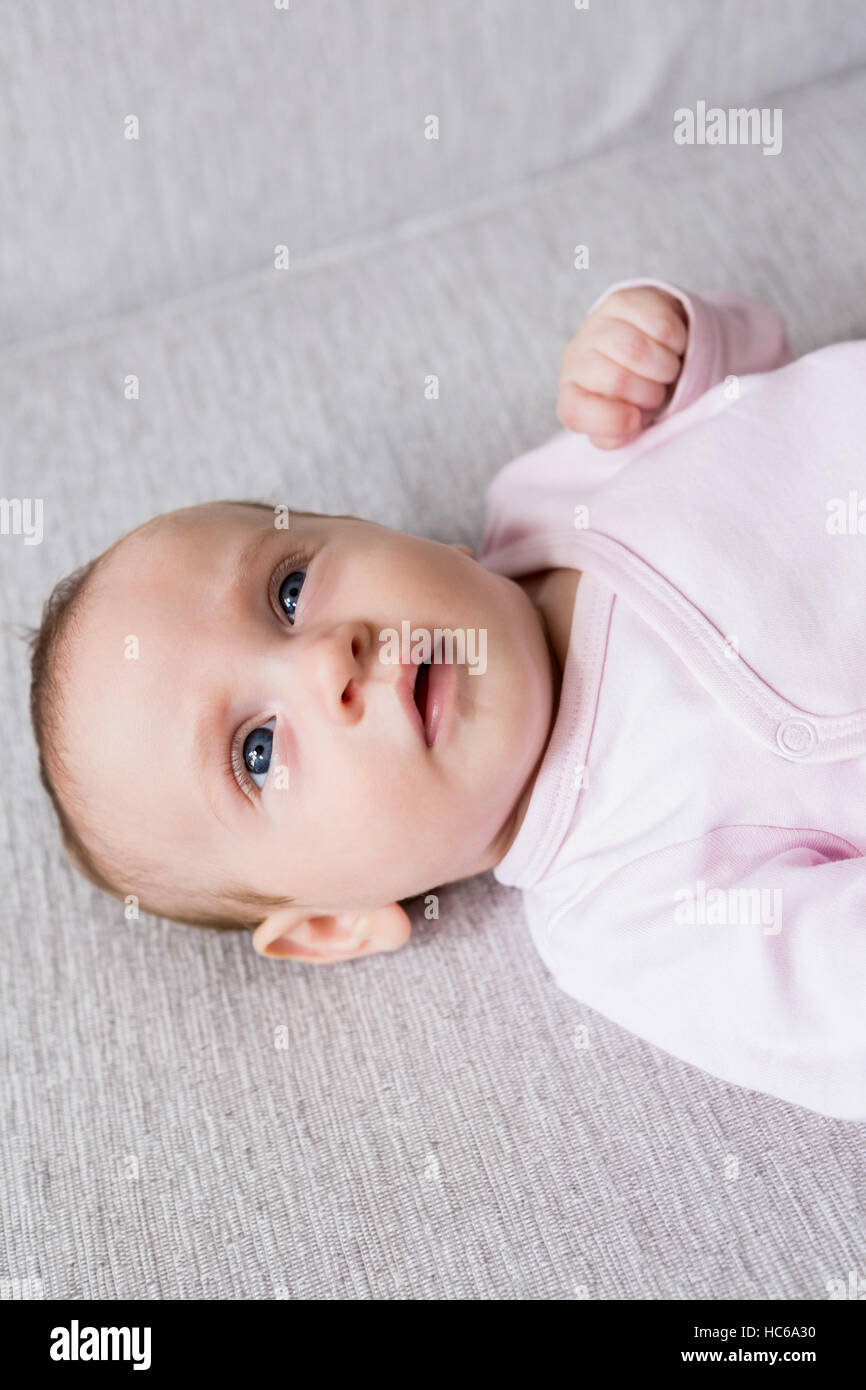 Baby lying on sofa in living room Stock Photo