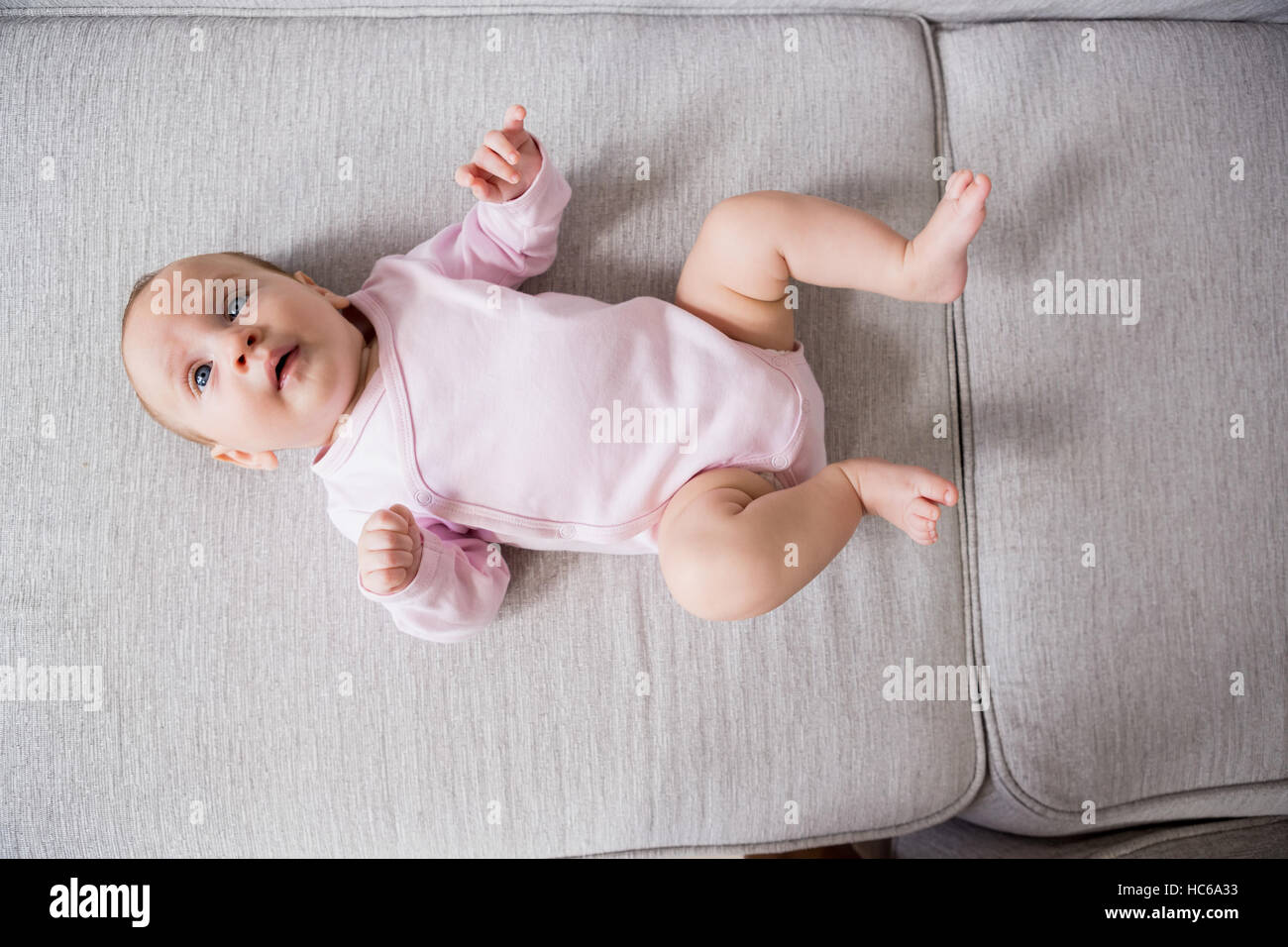 Baby lying on sofa in living room Stock Photo