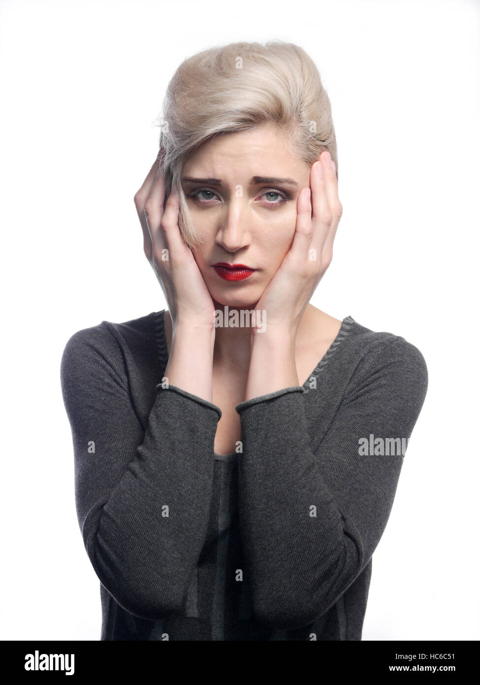 A image of a worried woman holding her hands up to her face. Stock Photo