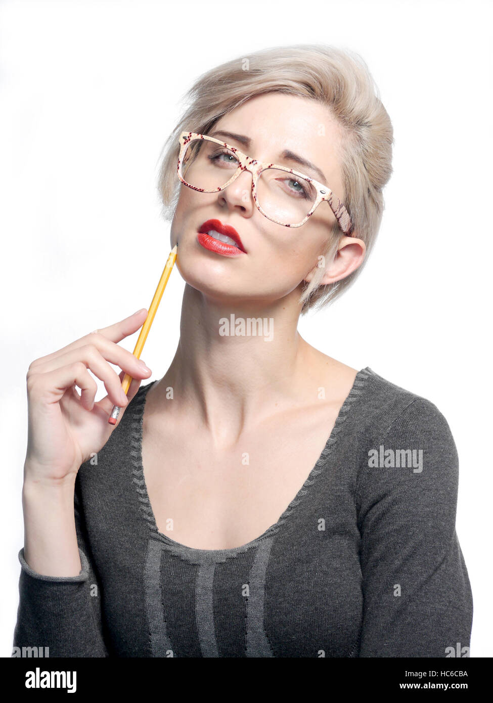 A attractive blonde haired woman is holding a yellow pencil and wearing glasses. Stock Photo