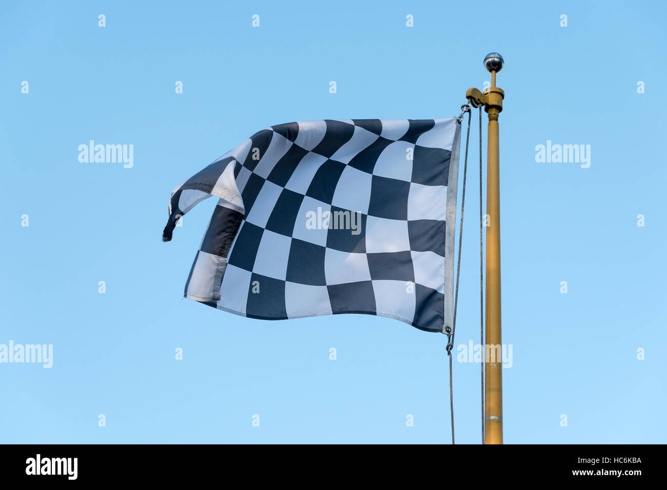 Checkered Flag blowing in wind on a flag pole Stock Photo