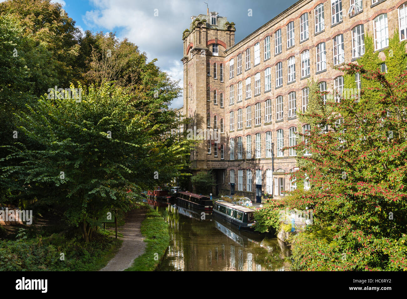 Clarence Mill - an old silk mill - on the banks of the Macclesfield Canal in Bollington Cheshire with moored narrow boats. Stock Photo