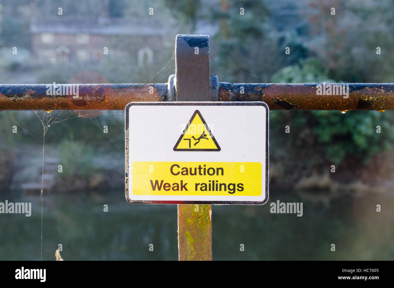 Sign saying 'caution weak railings, on the bank of the River Severn in Ironbridge Stock Photo