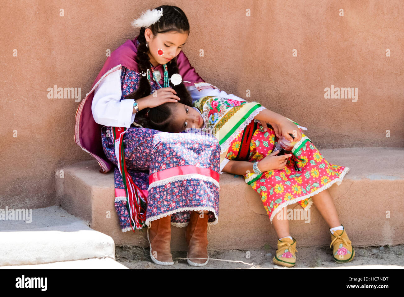 Ohkay Owingeh Pueblo, New Mexico, United States.  Summer Feast Day Celebration.  Tewa tribe. Big sister takes care of little sister after a long day d Stock Photo