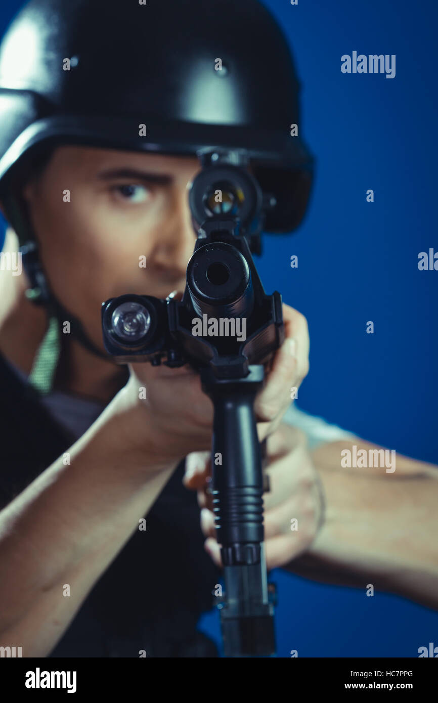 warrior paintball sport player wearing protective helmet aiming pistol