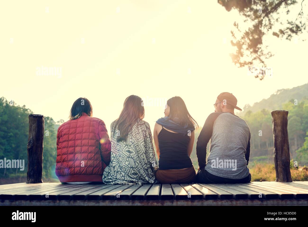 Friends Sitting in a Row Outdoors Concept Stock Photo - Alamy