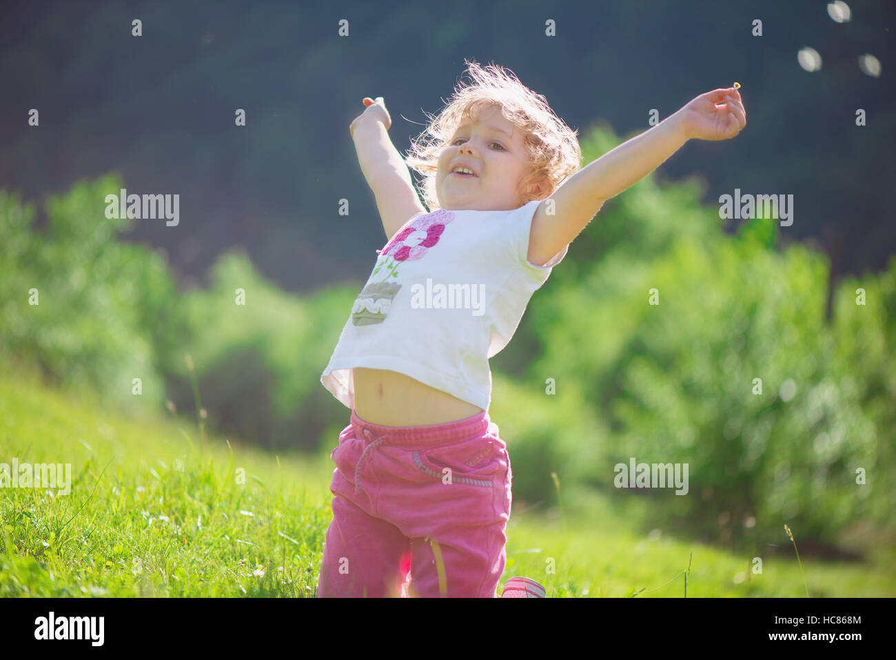Cute little girl playing at sunny green meadow Stock Photo - Alamy