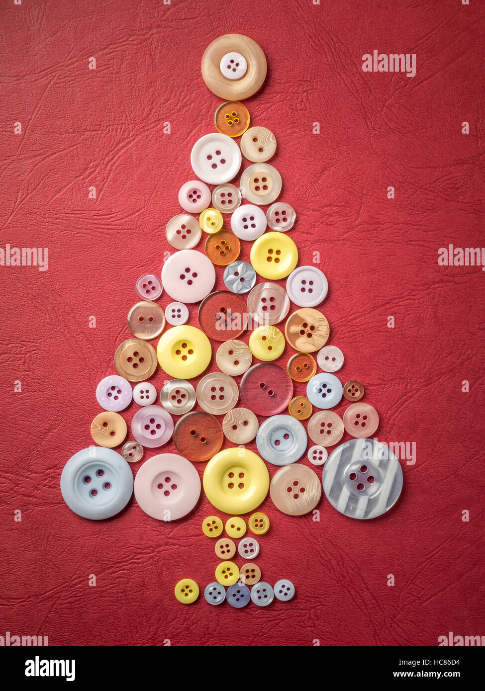 Christmas tree formed of apparel buttons on red textured background Stock Photo