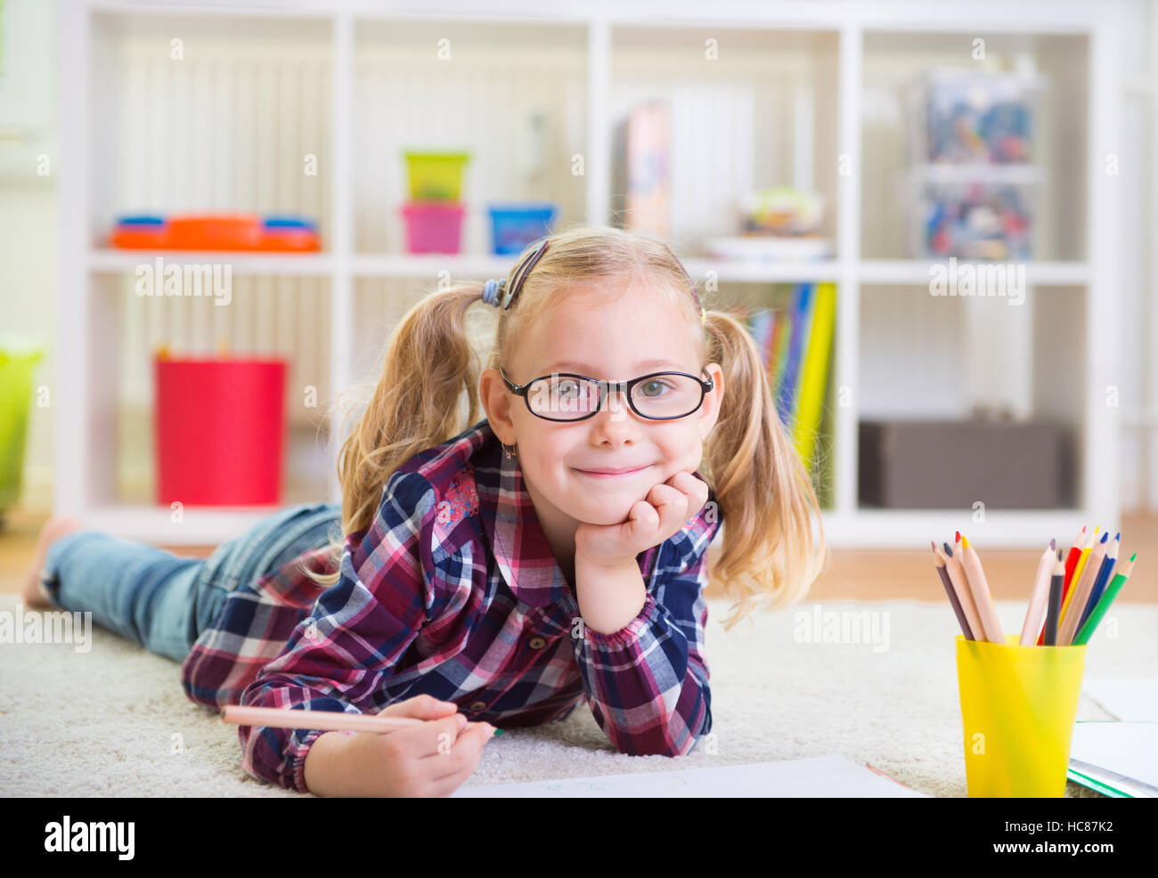 Cute little girl laying on floor at home Stock Photo - Alamy