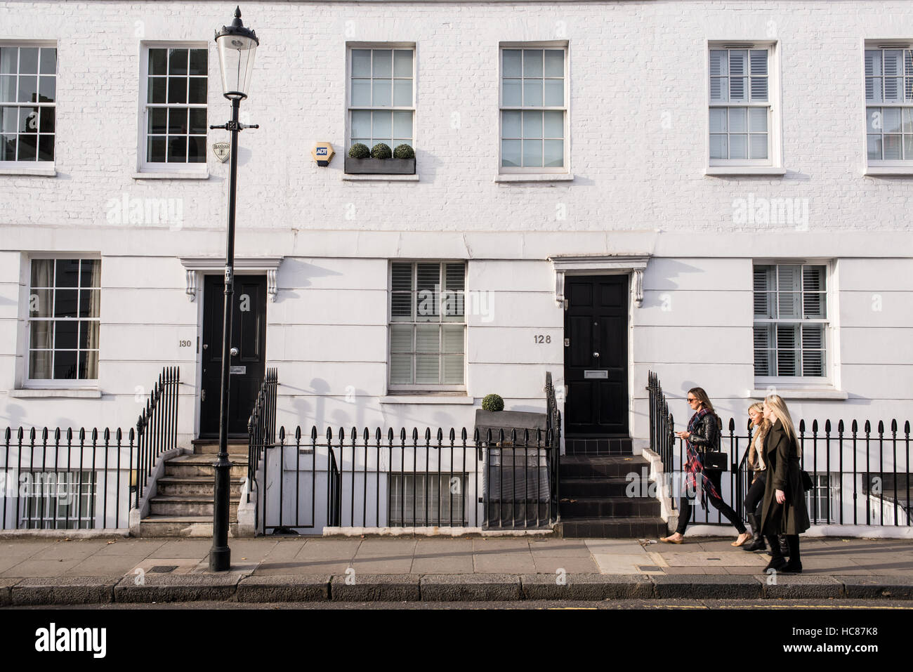 Three young women walking in a posh residential area of Chelsea, London, UK. Chelsea is an affluent area in southwest London Stock Photo