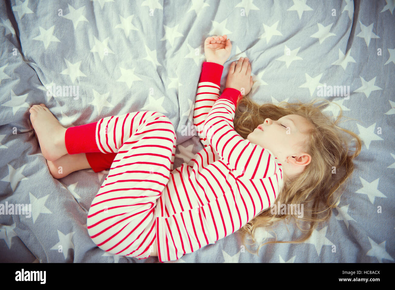 Cute little girl sleeps in striped pajames on bed Stock Photo - Alamy
