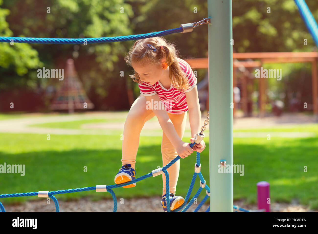 Happy little girl playing at playground in summer day Stock Photo - Alamy