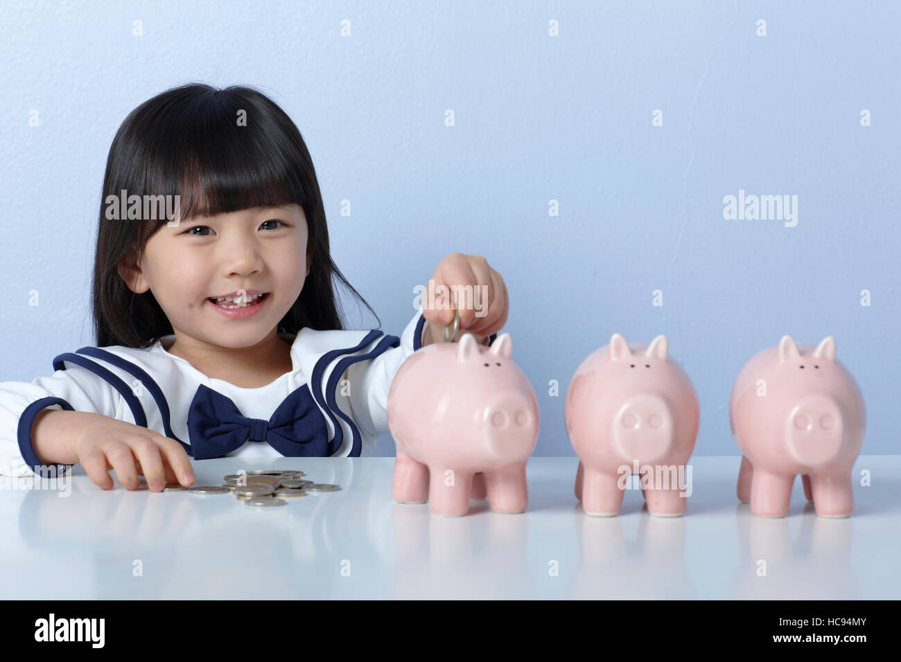 Portrait of smiling girl with piggy banks Stock Photo - Alamy