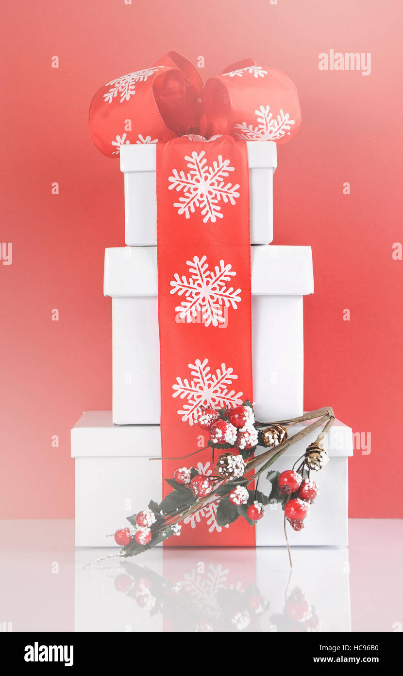 Stack of festive red and white theme Christmas gift boxes on reflective ...