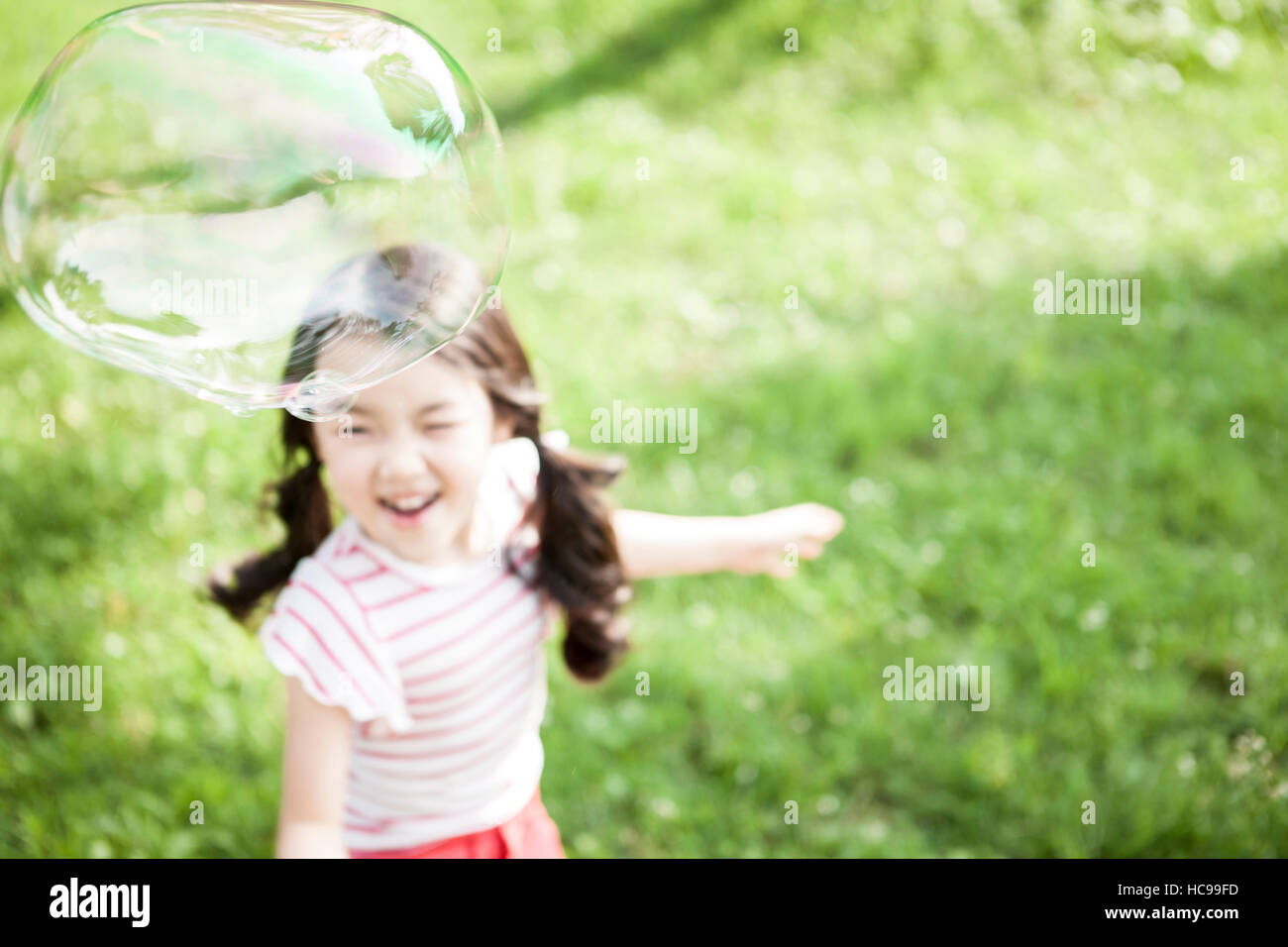 Smiling girl playing with bubble in field Stock Photo - Alamy