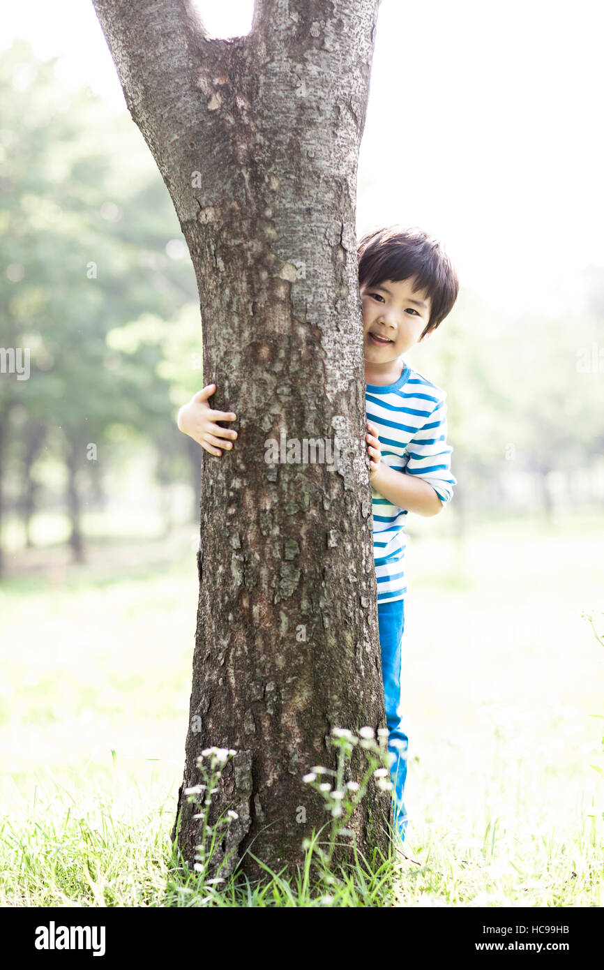 Smiling boy holding a tree in field Stock Photo