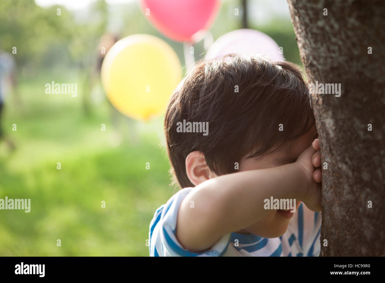 Portrait of smiling boy covering his eyes in field Stock Photo - Alamy