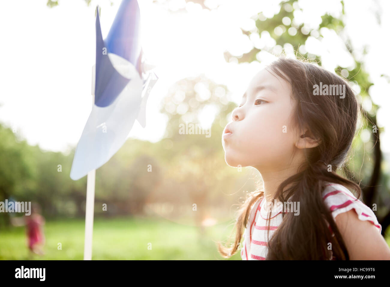 Portrait of girl blowing a pinwheel in field Stock Photo - Alamy