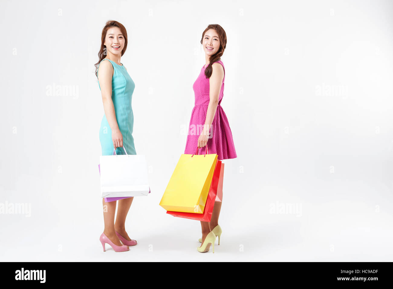 Two young smiling women with shopping bags standing Stock Photo - Alamy