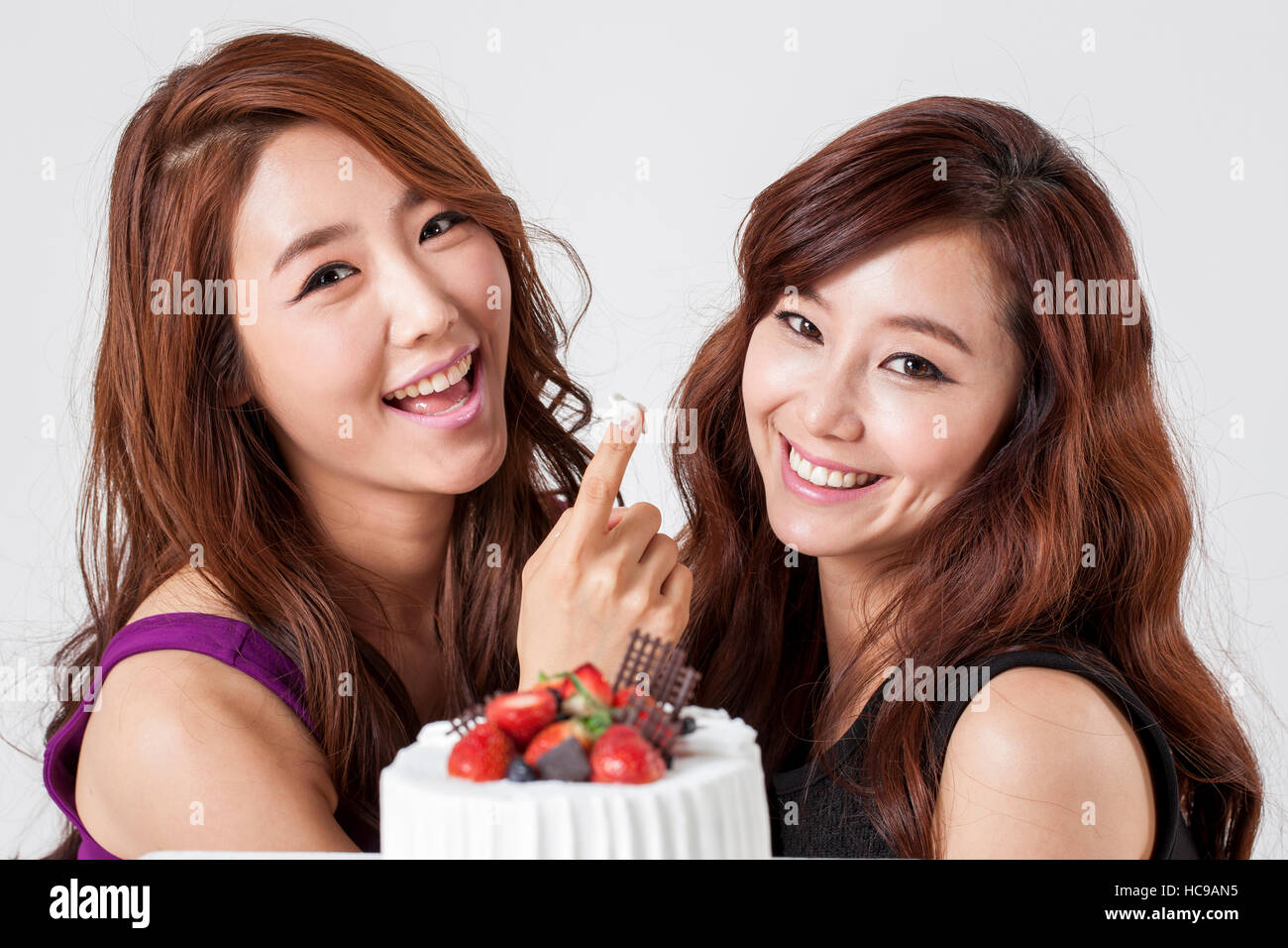Two young smiling women posing with a cake Stock Photo