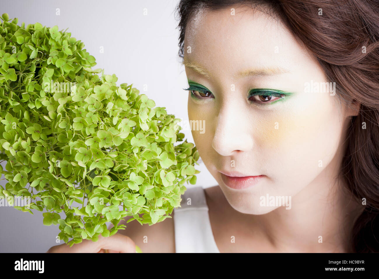 Portrait of young Korean woman with green flowers Stock Photo