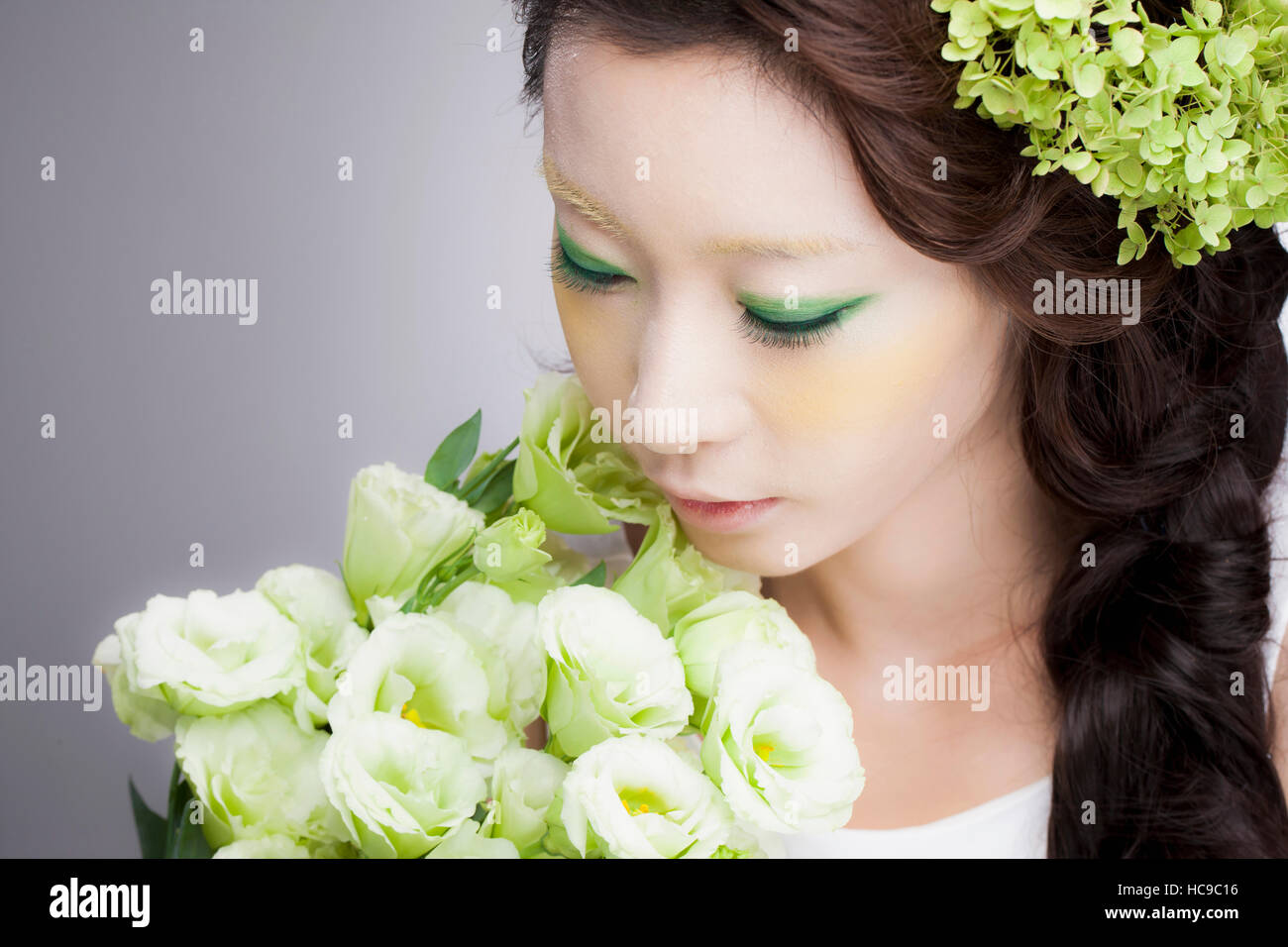 Portrait of young smiling Korean woman smelling flowers Stock Photo