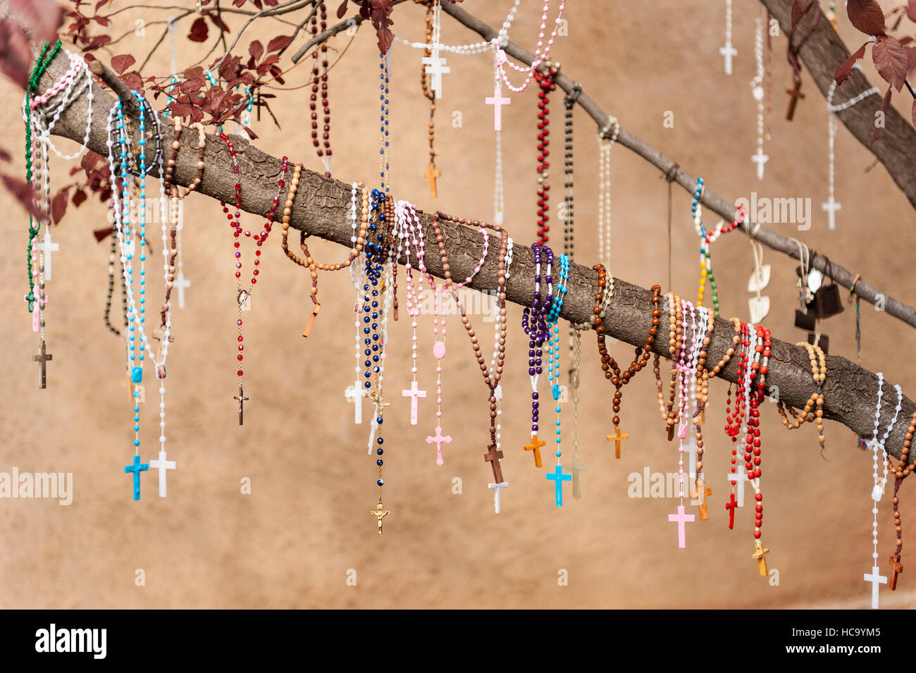 Several rosaries / prayers hanging from a tree branch at El Santuario de Chimayó, a Roman Catholic church in Chimayó, New Mexico Stock Photo