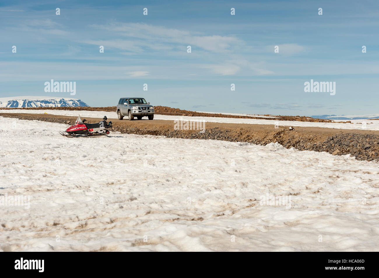 An off-road vehicle / 4x4 drives past a snowmobile on road F336, in Iceland. Stock Photo