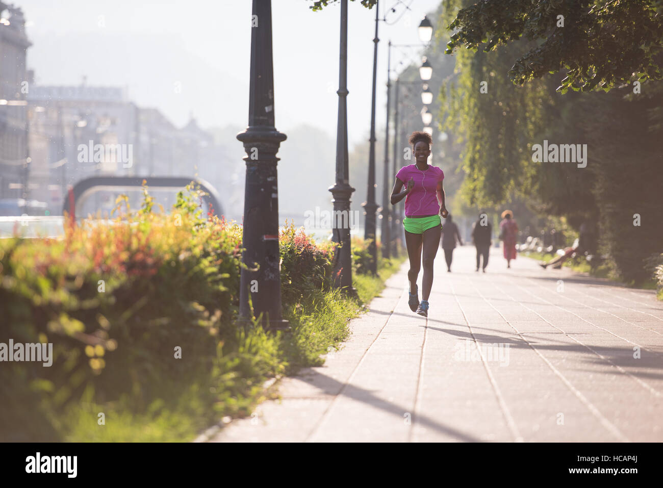 Beautiful young sporty african american woman running at early morning