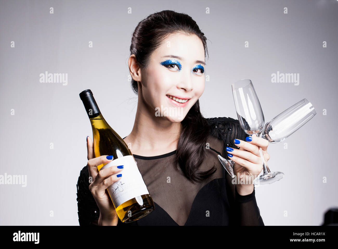 Portrait of smiling Korean woman in blue eye shadow holding champagne ...