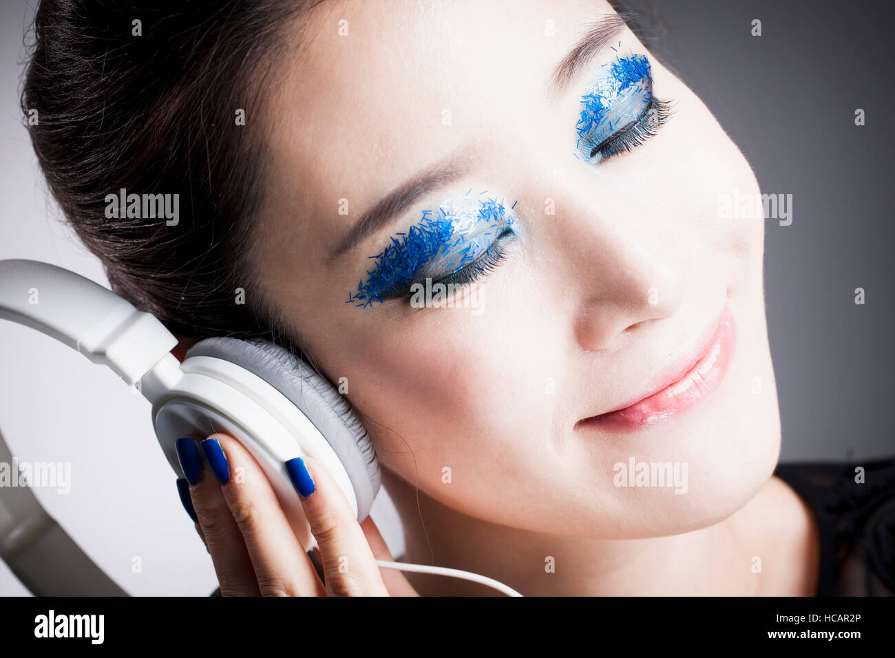 Portrait of young smiling Korean woman in blue eye shadow closing her ...