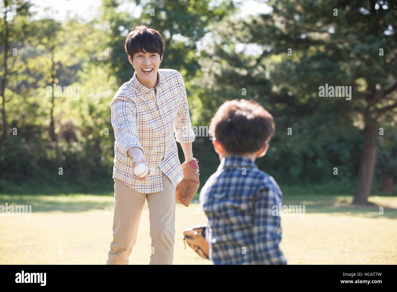 Loving father throwing a ball to his five-year-old son on grassland Stock Photo