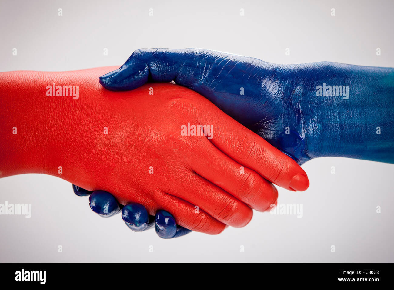 Red and blue hands shaking together Stock Photo
