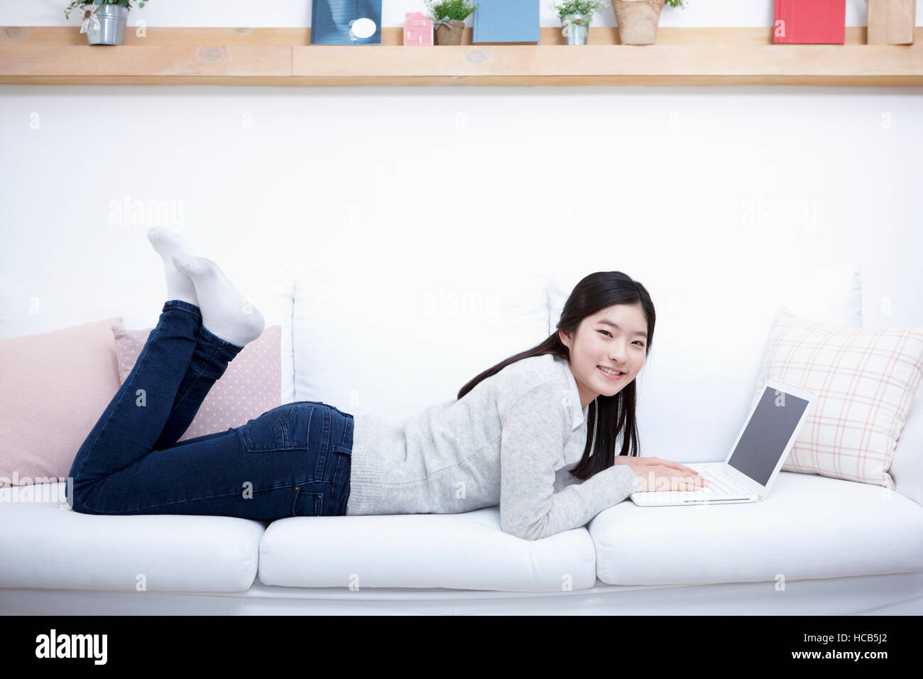 Smiling adolescent girl lying face down on sofa Stock Photo - Alamy