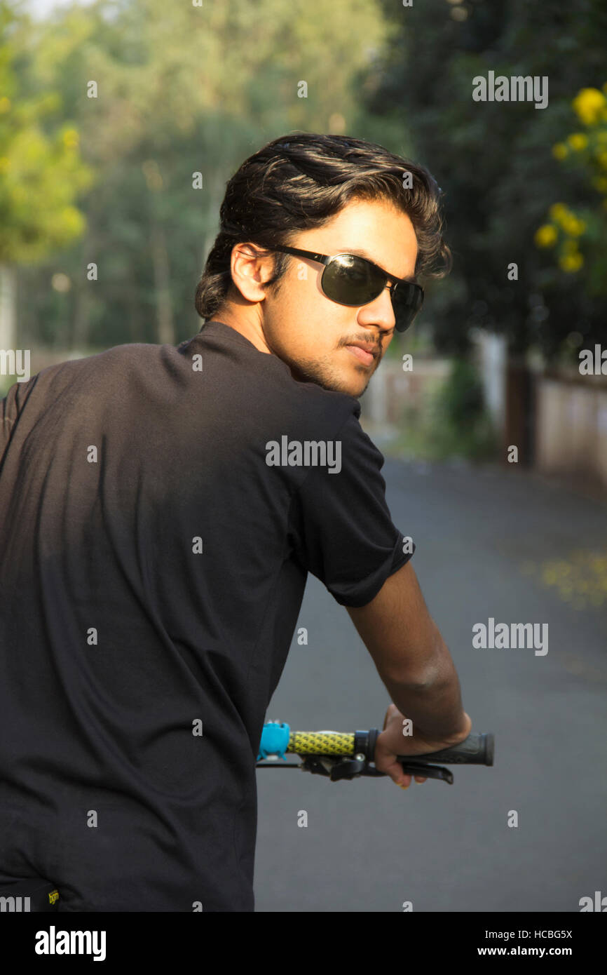 Young Indian boy wearing sun glasses and posing with bicycle Stock Photo