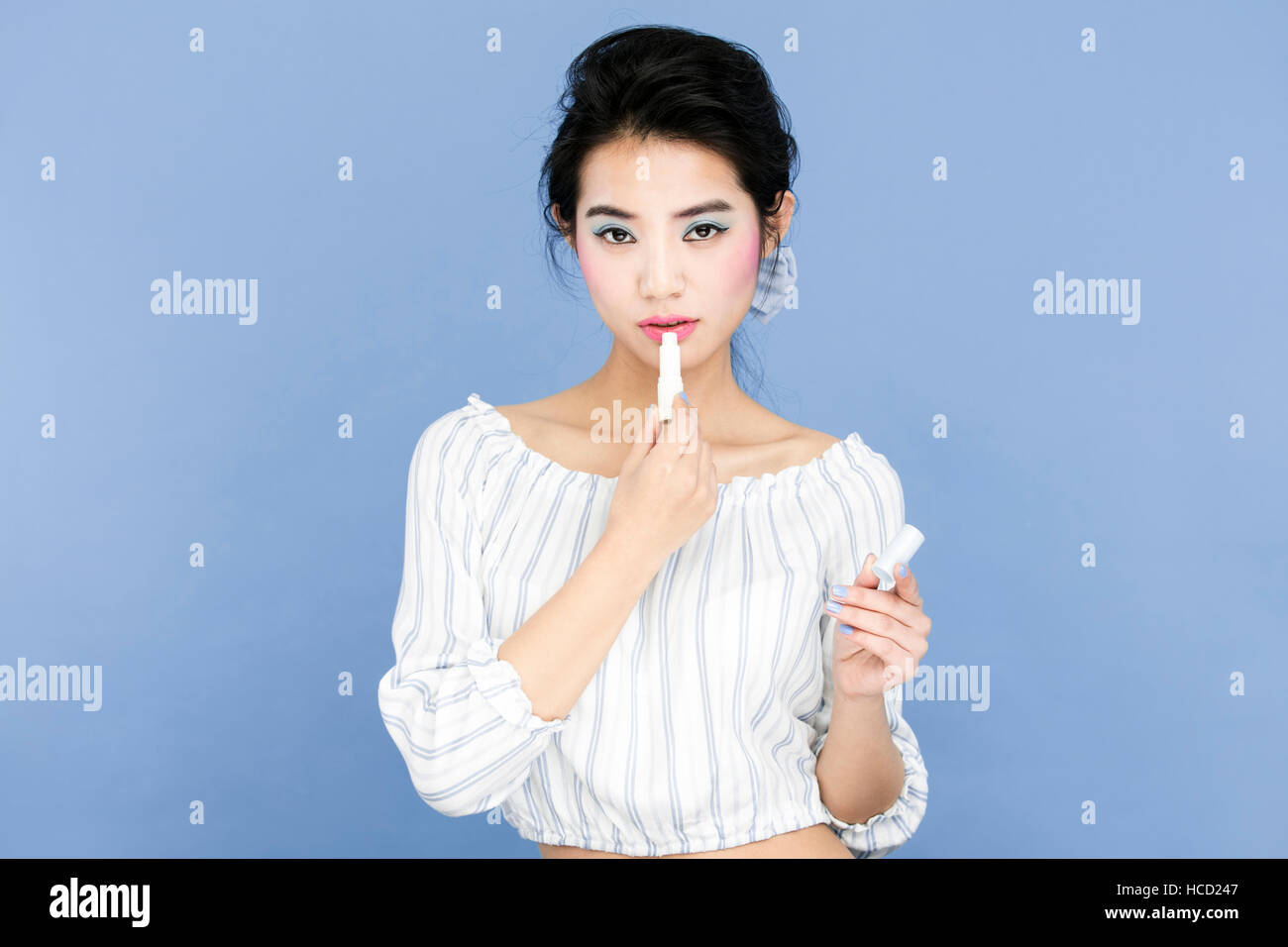 Portrait of young woman using lipstick Stock Photo